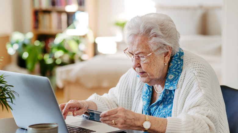 Elderly woman working on laptop, shopping online, risk of frauds and hoax for elderly people.
