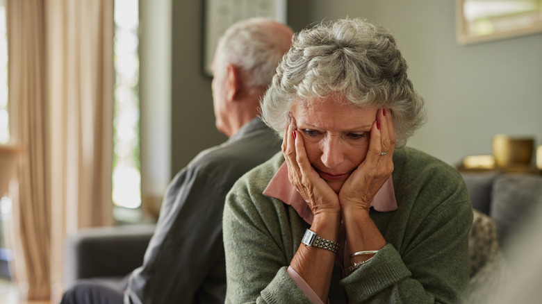 Older couple on a couch looking distressed