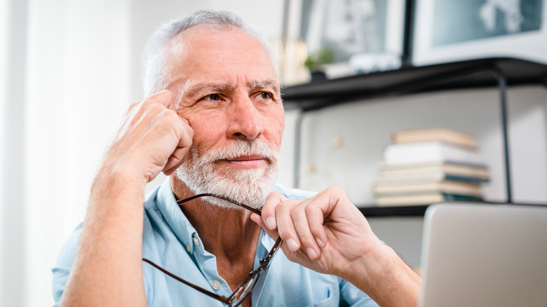 Older man with computer staring off
