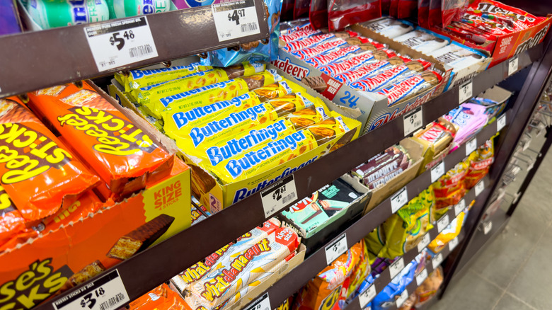 A candy display in a grocery store with prices visible for candy bars