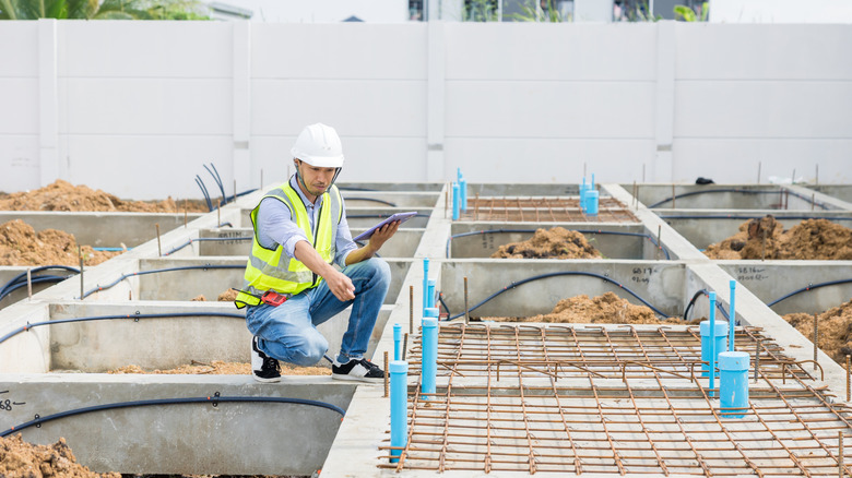 Unidentified man pointing at floor during foundation building