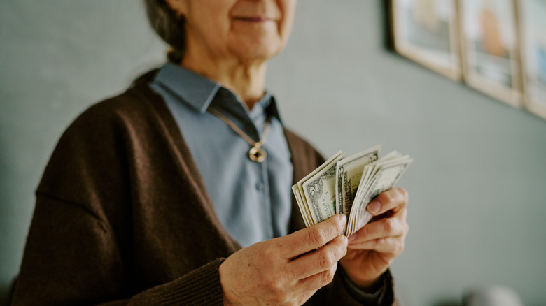 Unidentified older woman holding dollar notes