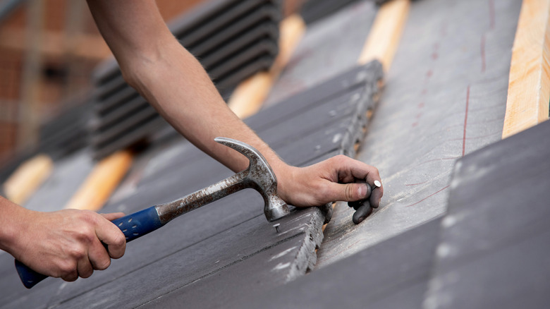 Unidentified person installing roof shingles