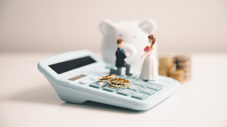 Marriage people figurines on a calculator with piggy bank