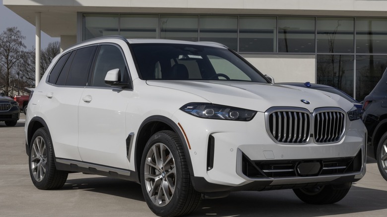 A white BMW X5 SUV parked outside a modern dealership building