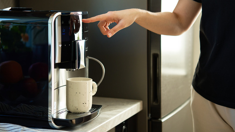 Unidentified person pressing a button on countertop coffee machine