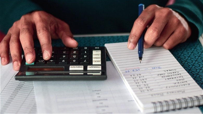 Person holding pen, calculating budget