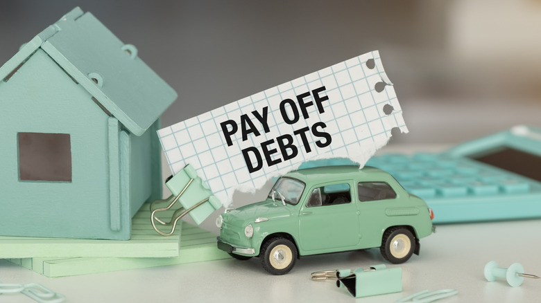 note reading pay off debts over car and house figurines