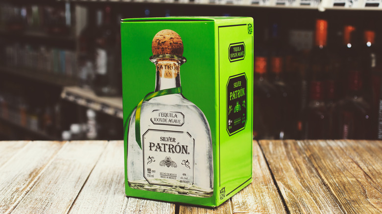 A green box with a picture of a bottle of Patrón Silver tequila sitting on a wood table.