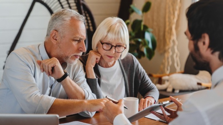 An elderly couple looking over documents in an office with a professional sitting across from them