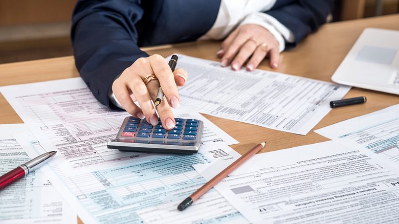 Woman filing tax forms using calculator