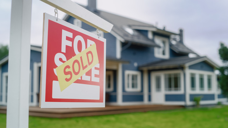 A for sale sign with the word 'sold' over it in front of a home