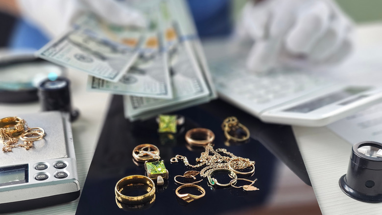 A jeweler paying a client cash and weighing their jewelry
