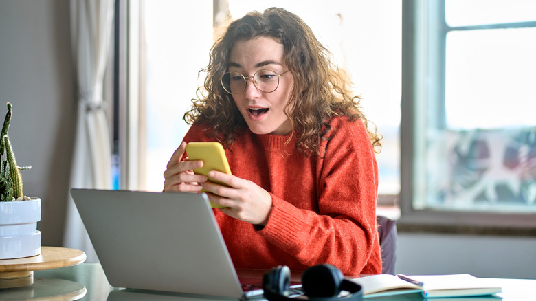 Young woman happily looking at her phone