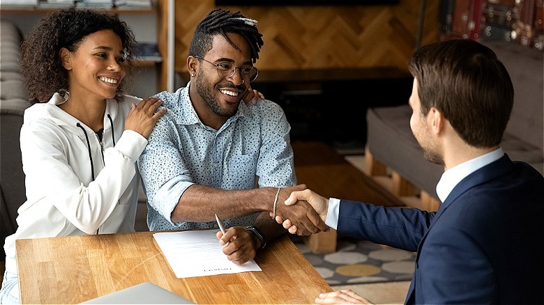 Couple smiling, shaking adviser's hand
