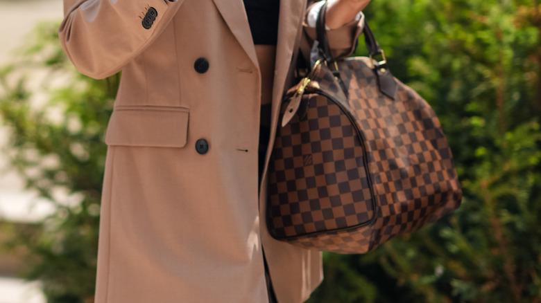 Stylish woman carrying Louis Vuitton Speedy bag