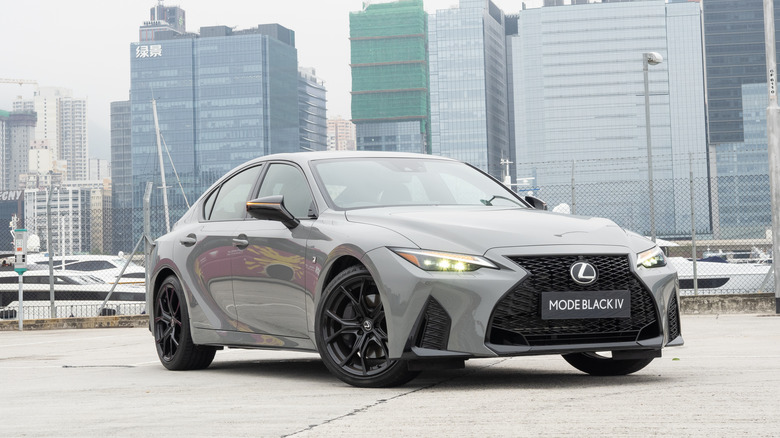 A grey Lexus IS parked in a city.