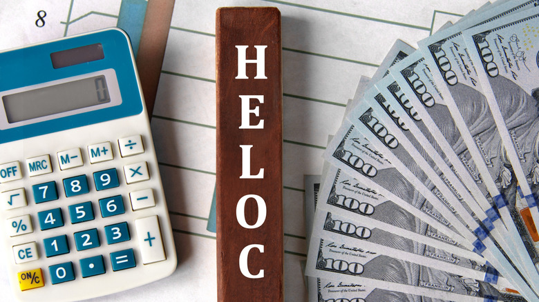 HELOC - acronym on brown wooden blocks on the background of a graph and banknotes.
