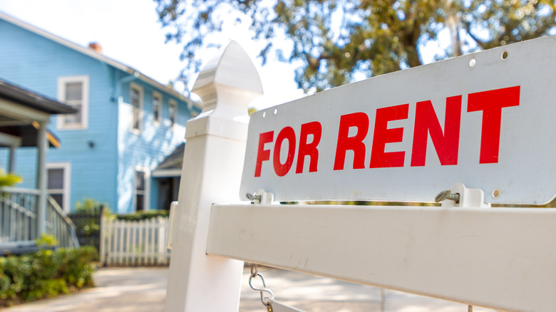A white and red sign advertises a house for rent.