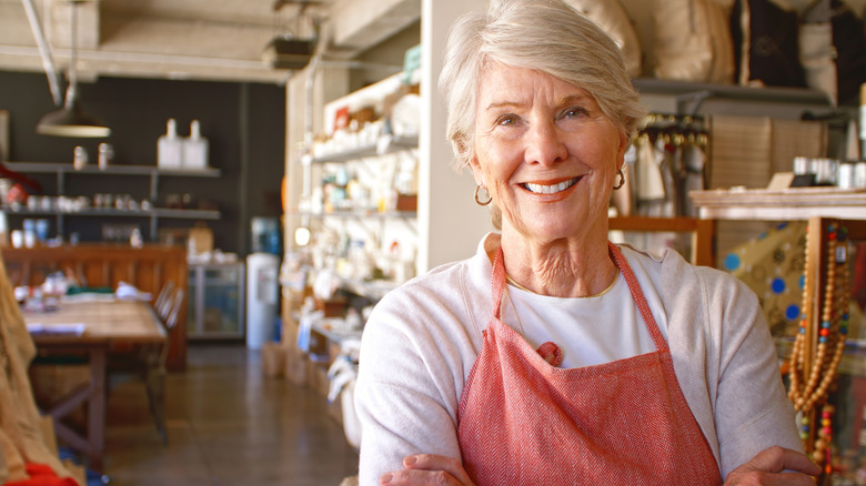Older woman with apron standing and smiling