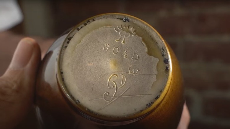 Hands holding Rookwood pottery with markings on the bottom