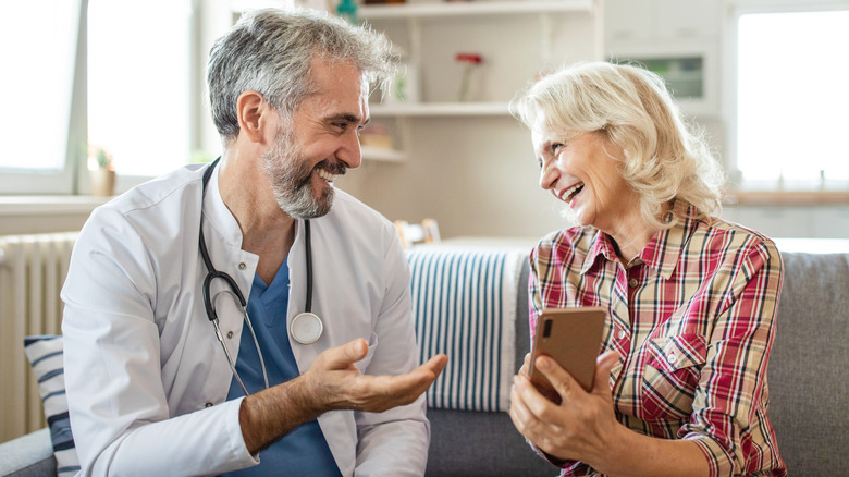 A male doctor and female mature patient smiling at each other in an office.