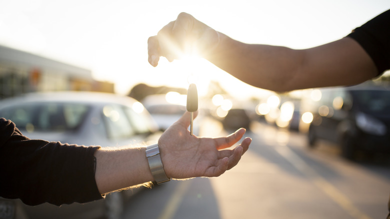 Car salesperson hands over keys to customer.