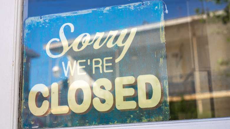 A "Sorry we're closed" sign in a storefront window