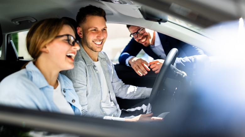 Young couple checking out the interior of a new car
