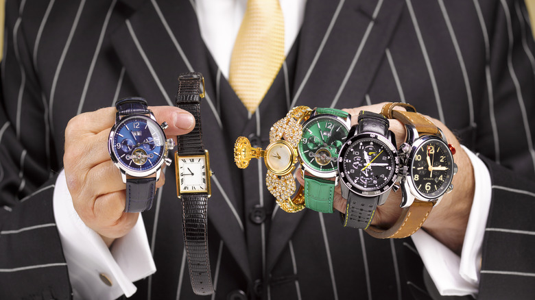 A salesman in a pinstriped suit holding several counterfeit watches.