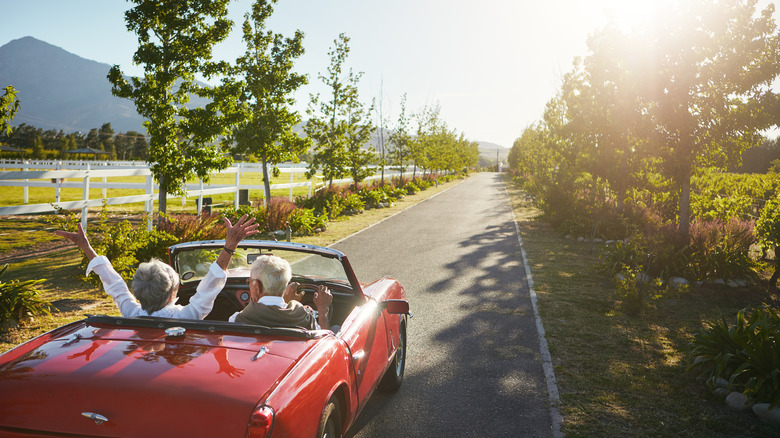 Senior couple driving a convertible car.