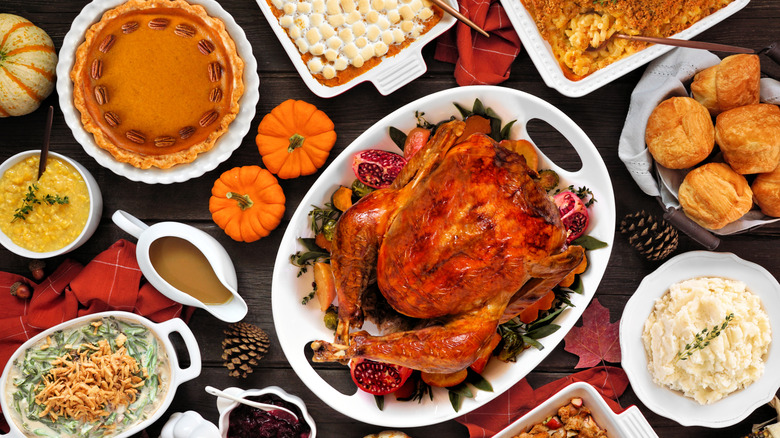 An overhead shot of a bountiful Thanksgiving meal complete with turkey, pie, mac and cheese, green bean casserole, and marshmallow-topped sweet potatoes