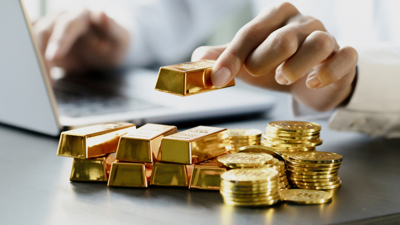 Person holding small bars of gold while working at their computer