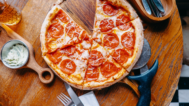 A pizza on a table with utensils