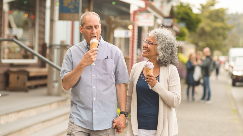 A senior couple holding hands and enjoying ice cream in a small town