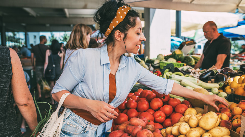 A Millennial woman buying produce at a farmer's market