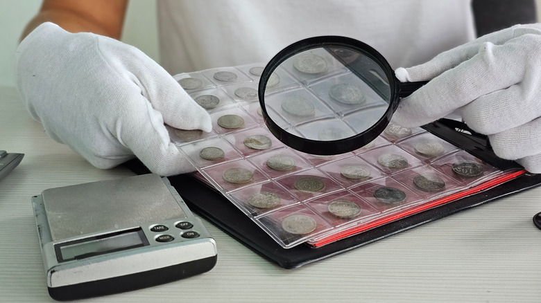 Expert examining coins with a magnifying glass