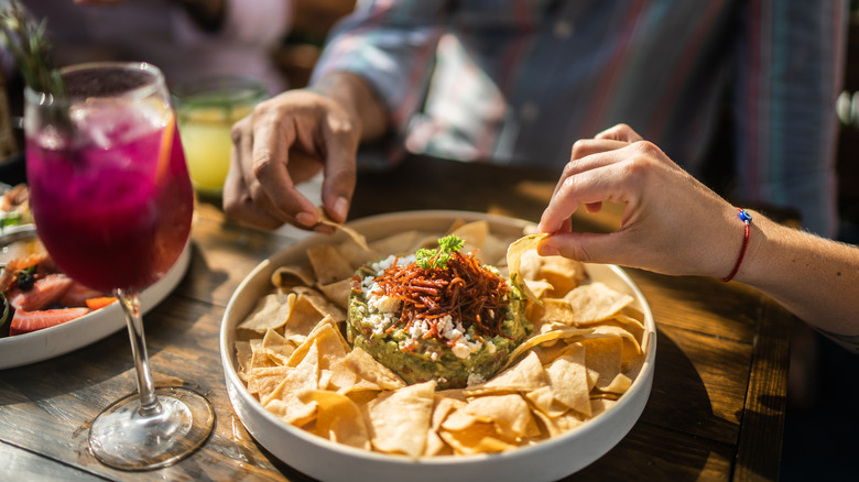 People sharing guacamole at a restaurant.