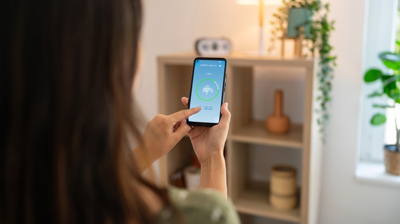 Woman controlling light with smartphone