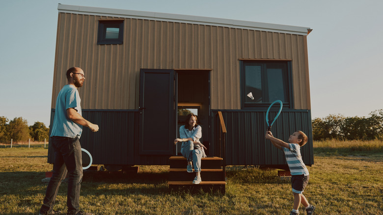 Family playing badminton outside a tiny house