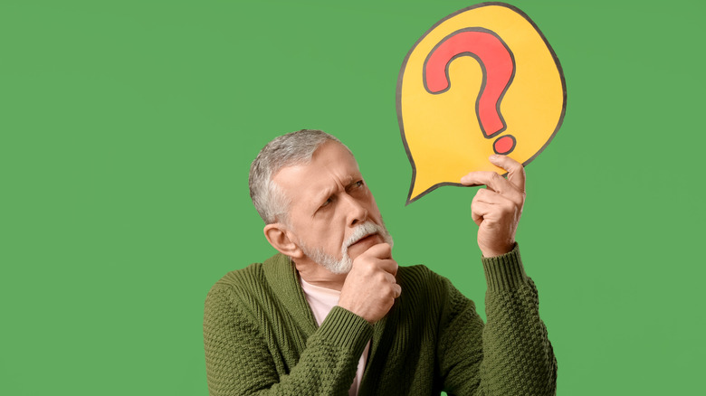 A contemplative man holding a thought bubble with a question mark in it.