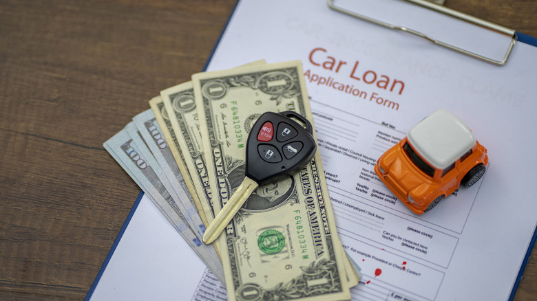 A small toy car on a desk next to a car loan application