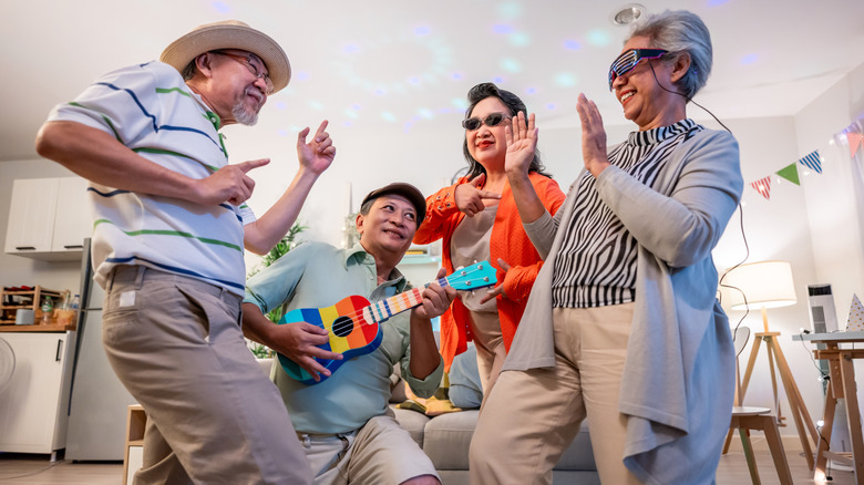 A group of seniors having a dance party in a someone's home.