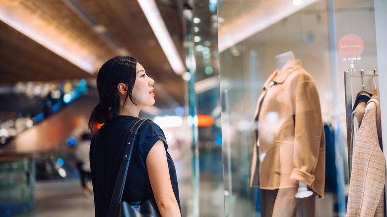 Woman looking at retail store window display inside mall
