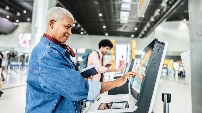 Woman checking in at airport kiosk