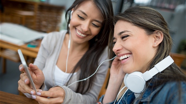 Two people smiling, sharing music