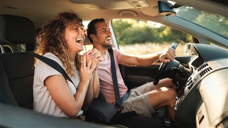 Couple driving car and laughing