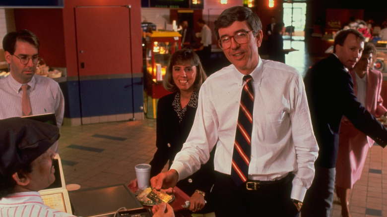 Chief of Sears Roebuck's Discover Card operation Thomas R. Butler paying for lunch at cafeteria w. Discover card.
