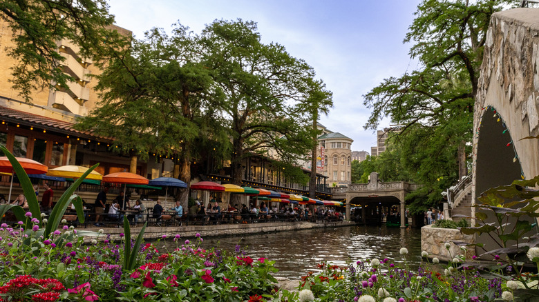 people dining beside the riverwalk in san antonio