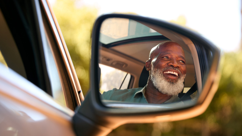 smiling mature man reflected in car mirror